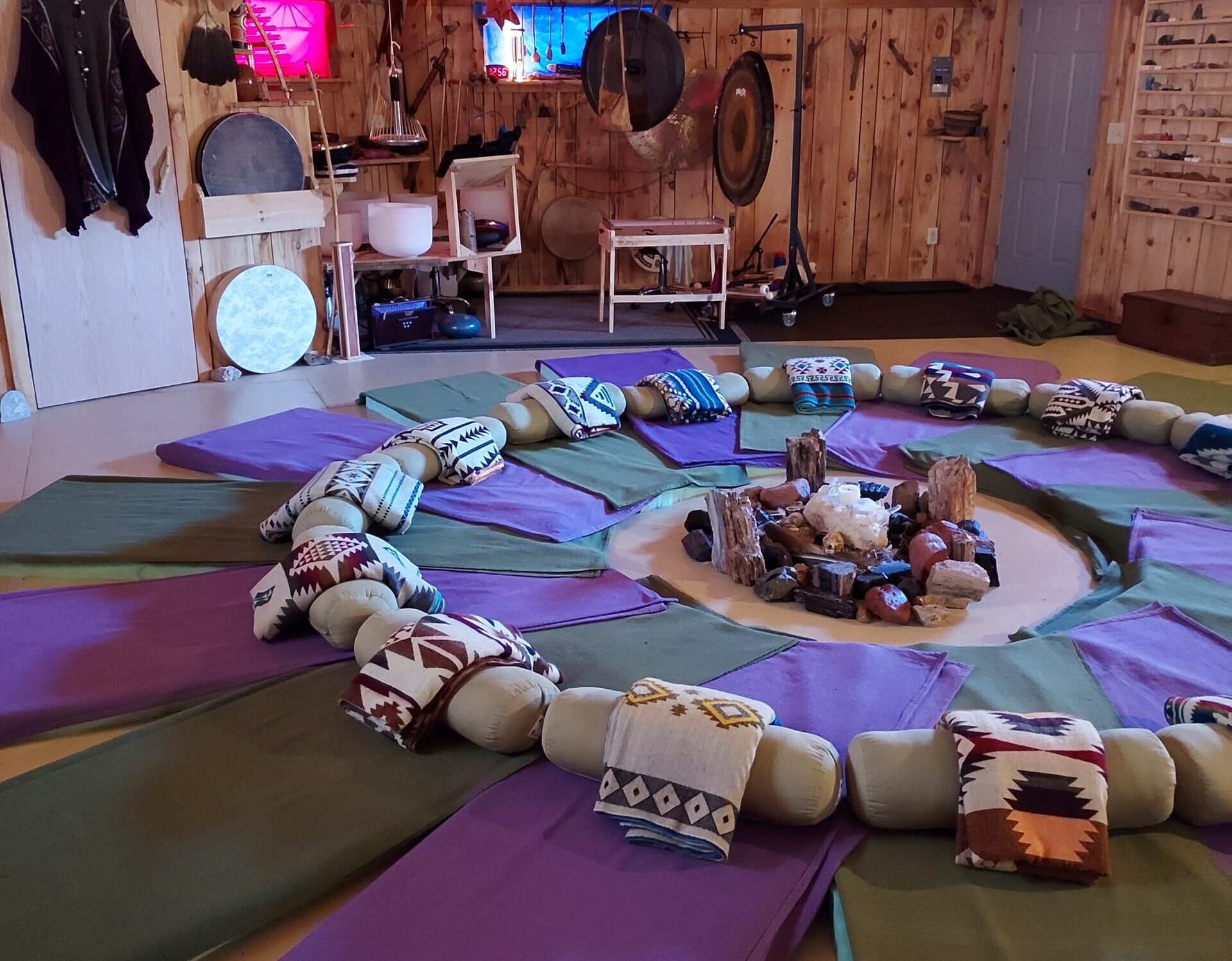 A peaceful circle of floor mats with blankets surrounded by sound meditation instruments and crystals