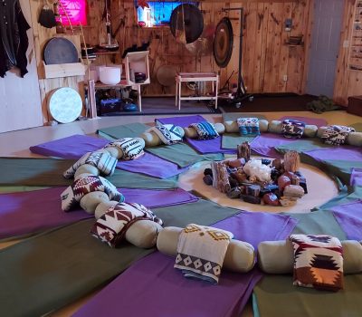 A peaceful circle of floor mats with blankets surrounded by sound meditation instruments and crystals